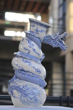 a blue and white vase sitting on top of a table in front of a building