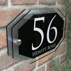 a close up of a street sign on a brick wall near a plant with leaves