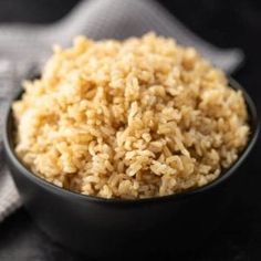 brown rice in a black bowl on top of a table