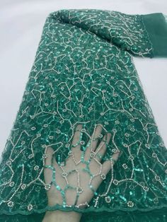 a hand that is on top of a piece of green cloth with beads and chains