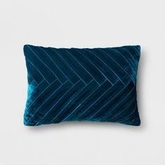 a blue velvet pillow on a white wall with an arrow design in the center and diagonal lines across it