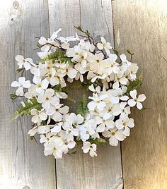 a wreath with white flowers hanging on a wooden fence