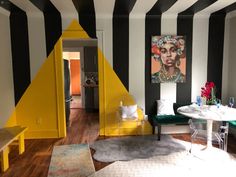 a living room with black and white stripes on the walls, yellow triangle rugs