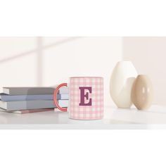 a coffee mug with the letter e on it next to some books and an egg