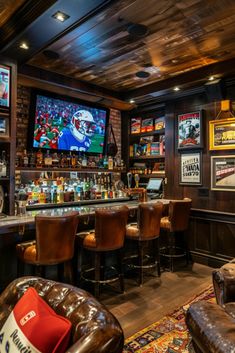 a sports themed bar with brown leather chairs and televisions on the wall behind it