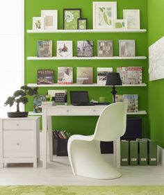 an office with green walls and pictures on the wall, white desk chair in front