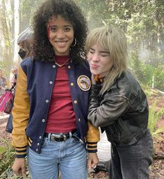 two young women standing next to each other in the woods, one with her face painted