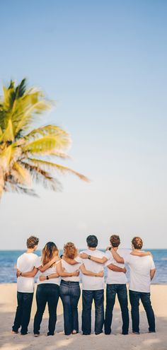 a group of young people standing on top of a sandy beach next to the ocean