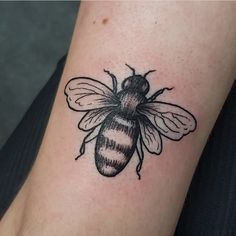 a black and white bee tattoo on the arm