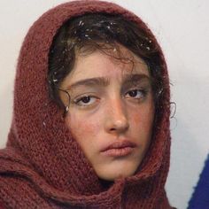 a young boy with freckled hair wearing a red scarf and hood over his head