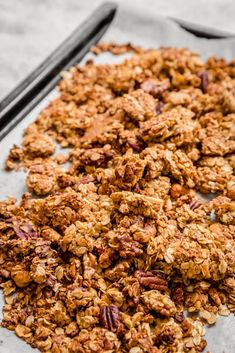 granola on a baking sheet with two black spoons