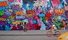 a person riding a bike in front of a wall covered with colorful grafitti