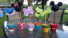 mickey mouse cupcake toppers are sitting on a table in front of some cups