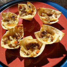 small appetizers with meat and vegetables are on a red plate, ready to be eaten