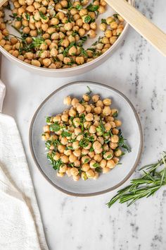 chickpeas and greens in a bowl next to a wooden spoon on a marble table