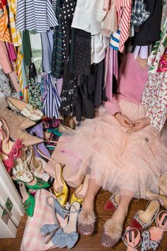 a woman sitting on the floor surrounded by shoes