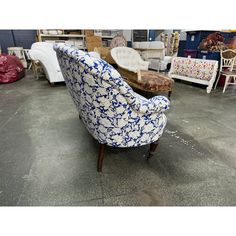 a chair with blue and white designs on it in a room full of chairs, couches and other furniture