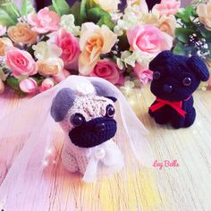 two small stuffed animals sitting next to each other on a wooden table with flowers in the background