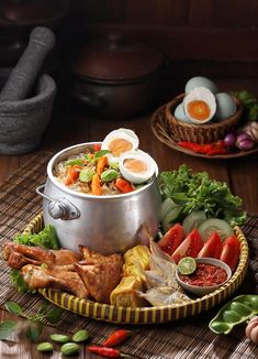 an assortment of food is displayed on a table with bowls and spoons next to it