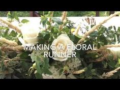 the words making a floral runner are in front of white roses and greenery with green leaves