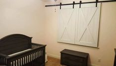 a baby's room with a black crib and white barn door on the wall