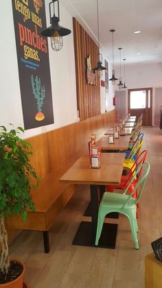 an empty restaurant with wooden tables and colorful chairs