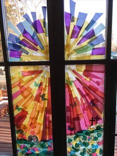 a stained glass window with the sun shining through it and colorful paper flowers in front