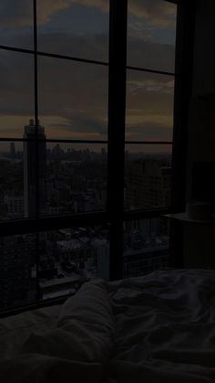 a bed sitting next to a window in a bedroom under a night sky filled with clouds