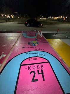 a pink skateboard with the number twenty on it sitting in front of a parking lot