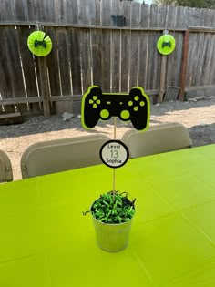 a green table topped with a potted plant next to a video game controller sign