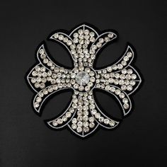 a black and white brooch with lots of diamonds in the shape of a cross