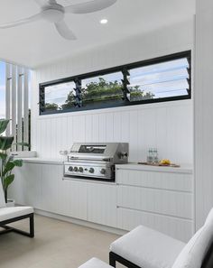 an outdoor kitchen with white walls and ceiling fans