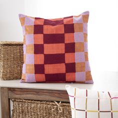 two pillows sitting on top of a wooden table next to wicker baskets and a window