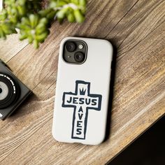 a phone case with the words jesus lives on it next to a camera and plant