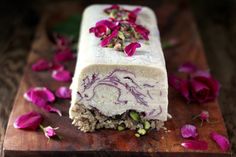 a piece of cake sitting on top of a wooden cutting board covered in purple flowers