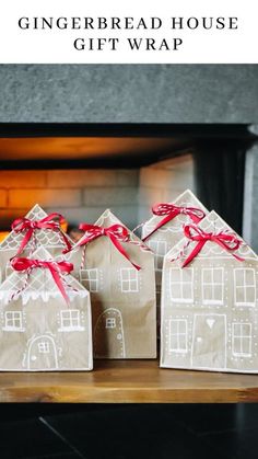 three gingerbread house gift bags tied with red ribbon, sitting on a fireplace mantel