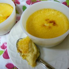 two bowls of soup and a spoon on a plate with a flowered tablecloth