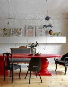 a red table and chairs in a room with white bricks on the wall behind it