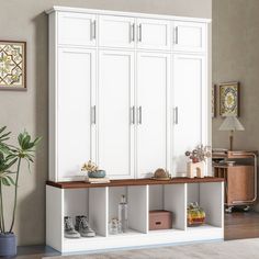 a large white cabinet with shelves and shoes on it next to a potted plant