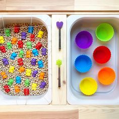 two trays filled with different colored cupcake liners next to each other on a wooden table