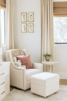 a white chair and ottoman in a room with beige drapes on the windowsill