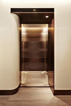 an empty elevator with the doors open and wood floors in front of it is lit by recessed lighting