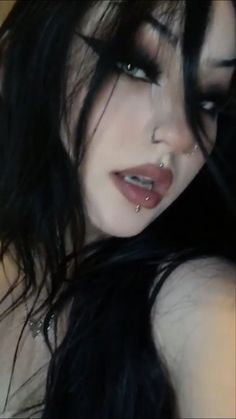 a woman with black hair and piercings on her nose is posing for the camera