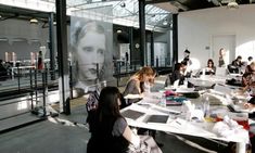 a group of people sitting around a table with laptops and papers on it in an office building