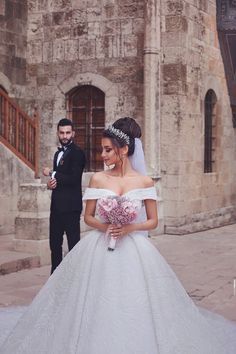 a bride and groom standing in front of an old building