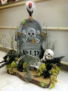 a tombstone with a bird on top of it next to some plants and fake skulls