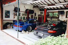 two cars parked in a garage next to each other and one dog laying on the floor