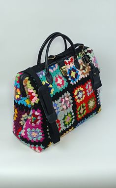 a multicolored handbag sitting on top of a white table next to a wall