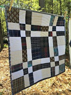 a black and white quilt hanging on a clothes line in the woods with trees behind it