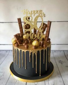 a black and gold birthday cake with chocolate candies on the top that says happy 30th